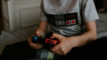 kid sitting on gray bed while playing